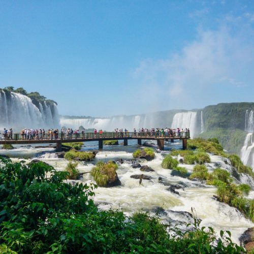 Iguacu Falls National Park, Brazil - Feb 08 2019: Iguacu Falls in Brazil. There are many waterfalls in this small area that borders Argentina. The waterfalls are really breathtaking. People can be seen on the bridge that goes out over the shallow part of the waterfall.